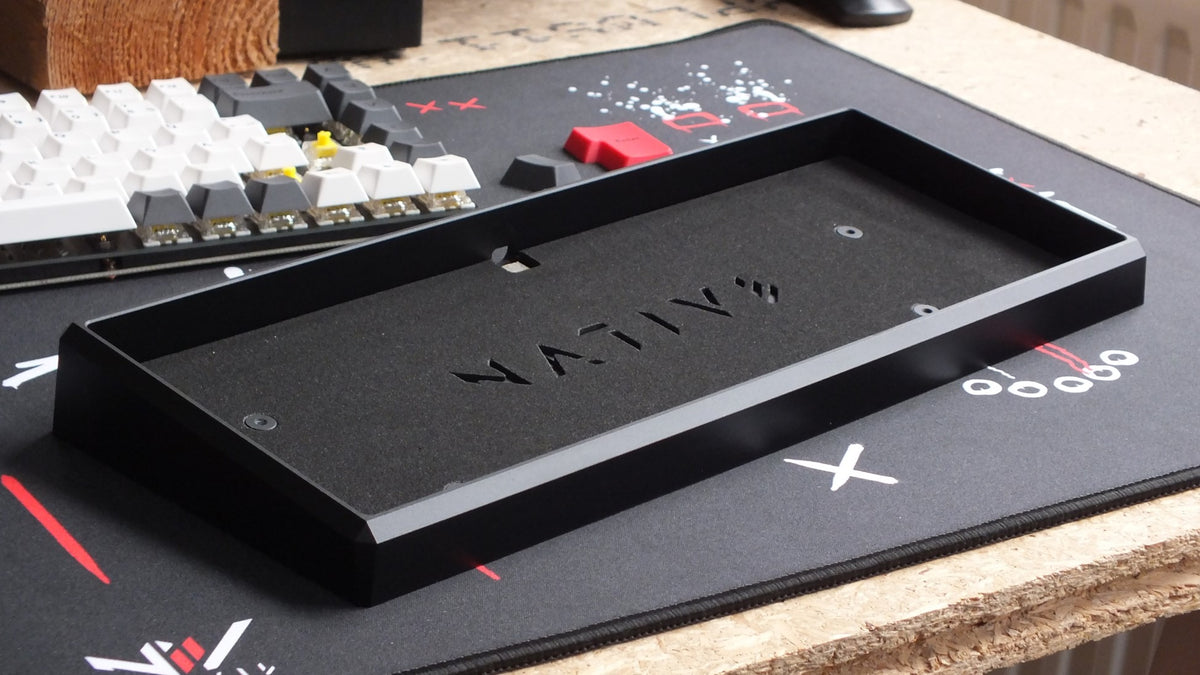 Leeres Gehäuse der NATIVE 75 von innen, im Hintergrund Keycaps auf einer ANVIL Deskmat